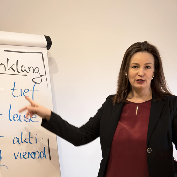Dozentin erklärt Stimmklang beim Stimmtraining vor dem Whiteboard.